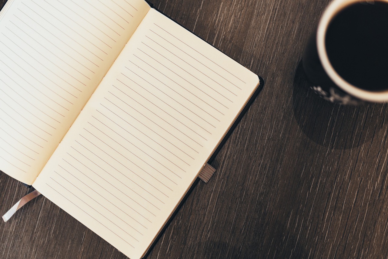Blank Notebook on a wood table with coffee cup